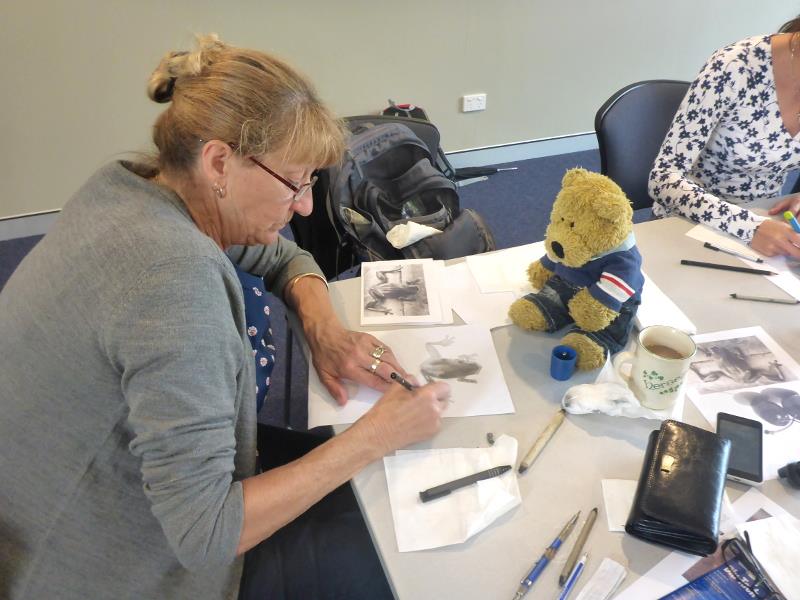 Gail concentrating on finishing her frog piece with Teddy supervising